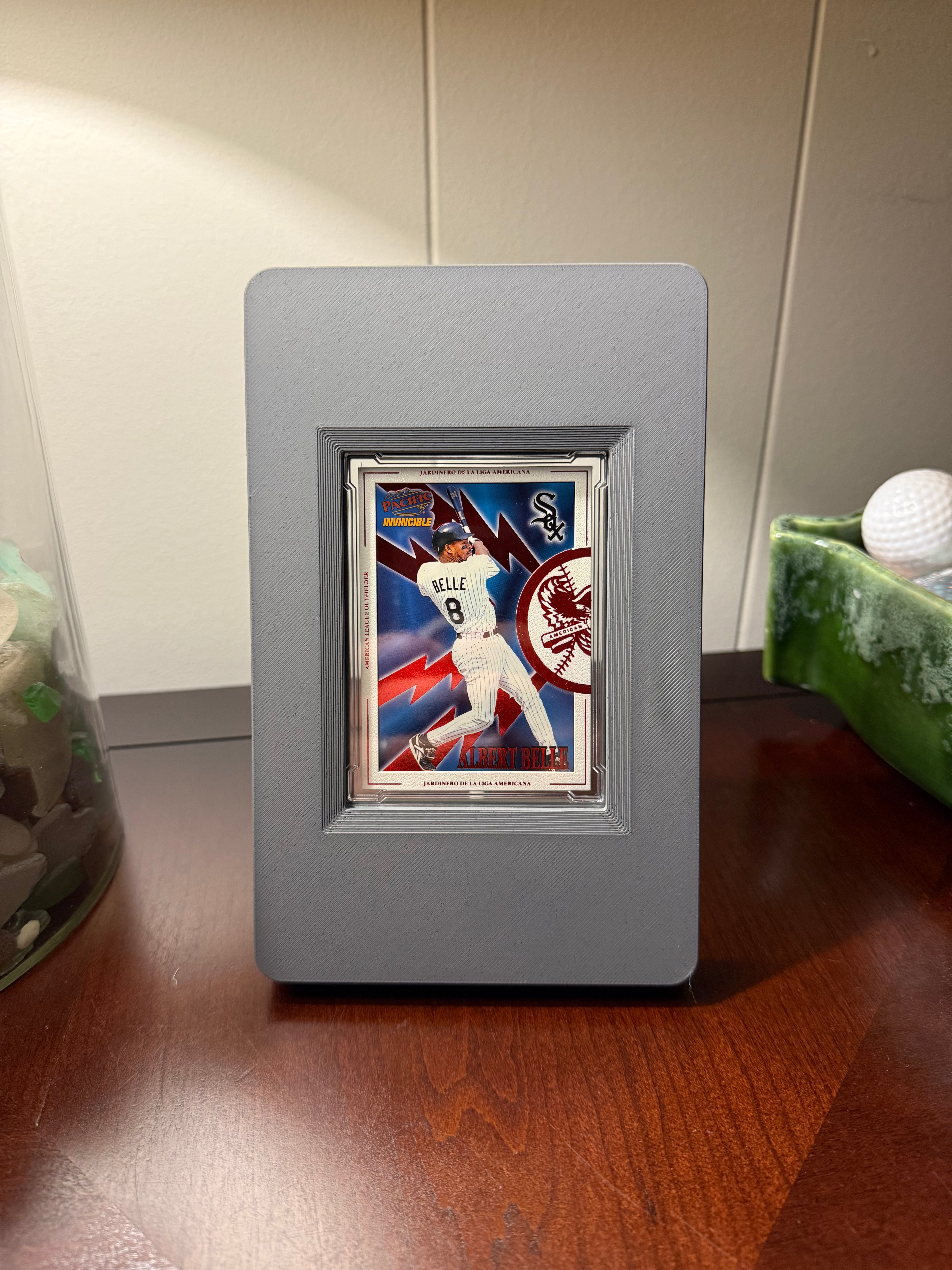 Framed baseball card of Albert Belle of the Cleveland Indians, Chicago White Sox, and Baltimore Orioles in a gray SlabGhost Raw frame on a wooden surface.