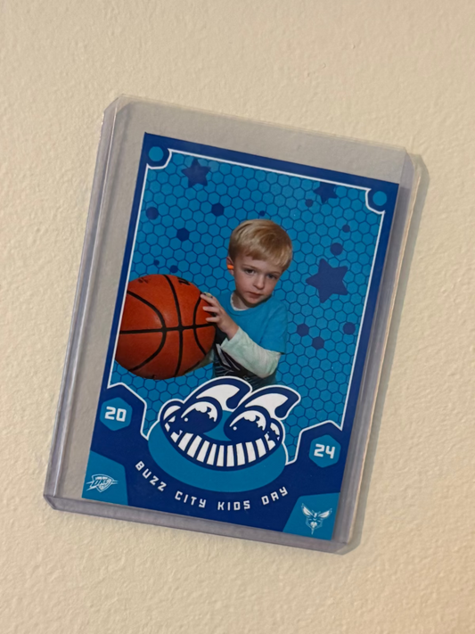 Trading card of a child holding a basketball with a blue border on a beige wall.